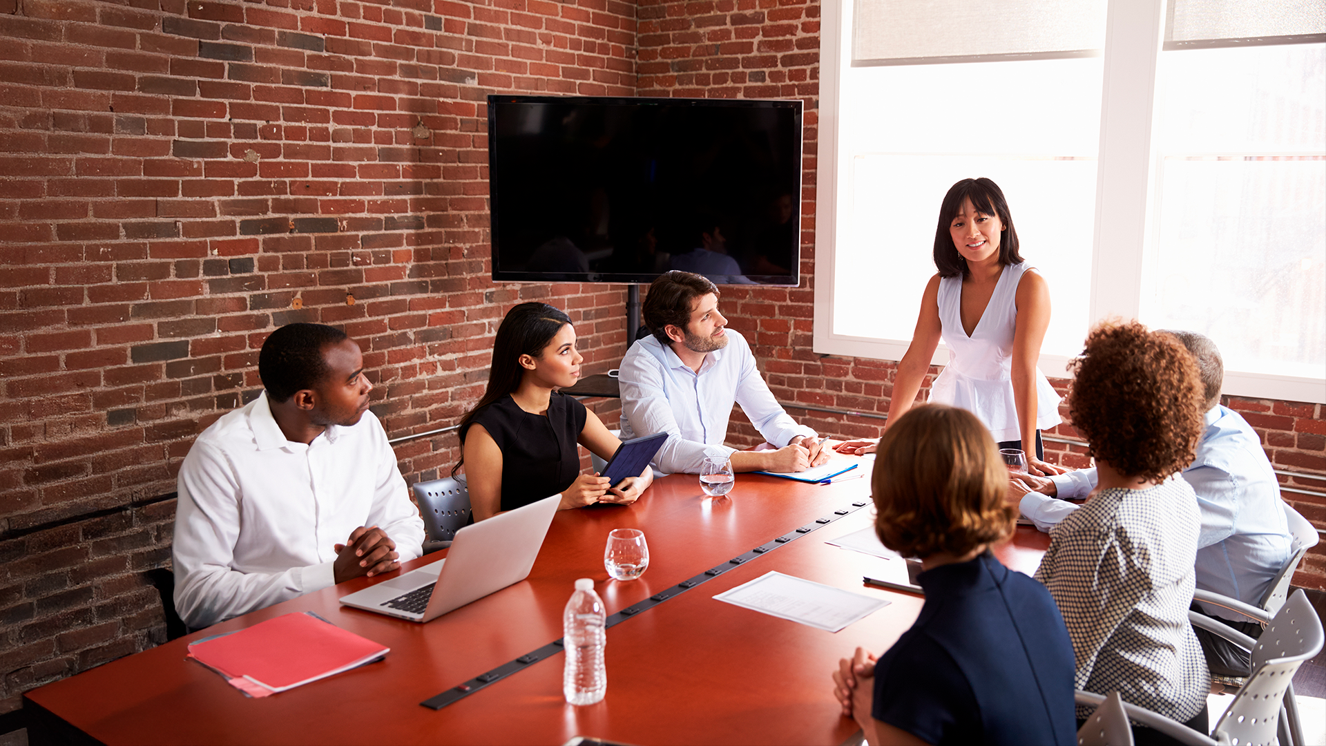 Grupo diverso de personas reunidas en sala de reuniones conversan alrededor de la mesa. ECE. Trimestre OND 2024.