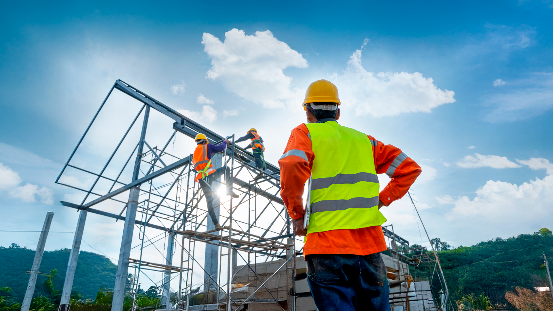 Imagen ilustrativa. Trabajador observa soldadores en estructura metálica de obra en construcción. Est. Cons. I Sem 2025. Preliminar.